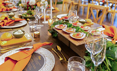 Formal dinner table setting with orange napkins, shellfish appetizers, and elegant tableware.