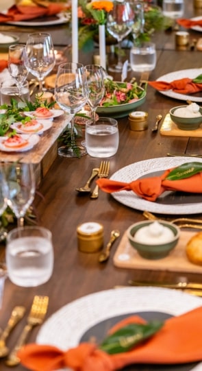 A beautifully set dinner table with elegant glassware, plates of food, and decorative napkins, arranged for a social event.