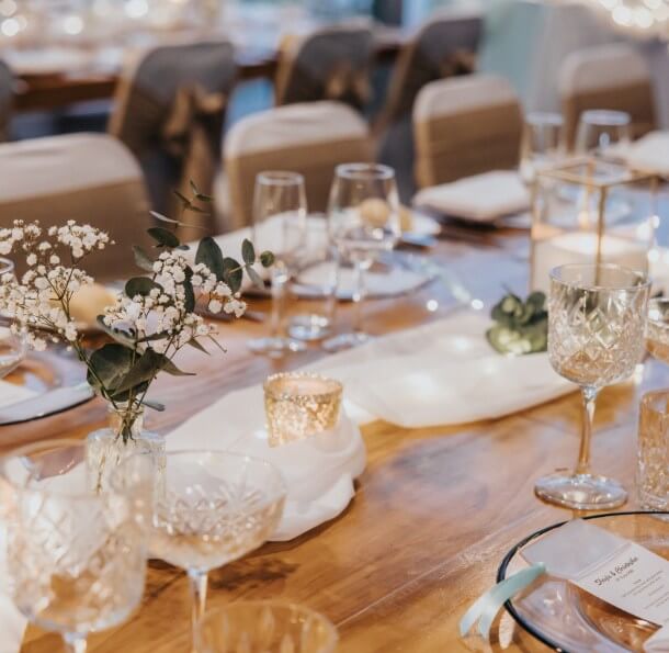 Close-up of an elegantly set wooden table with a white cloth runner