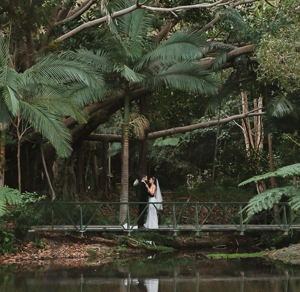 wedding couple stand in romantic bushland area next to pond