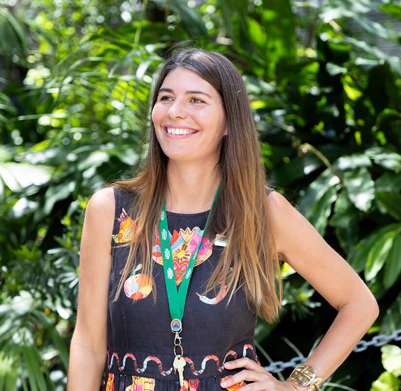 Smiling woman with long hair in a garden setting.