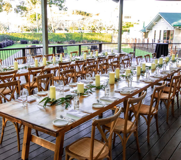 Outdoor dining setup with long wooden tables and candles.
