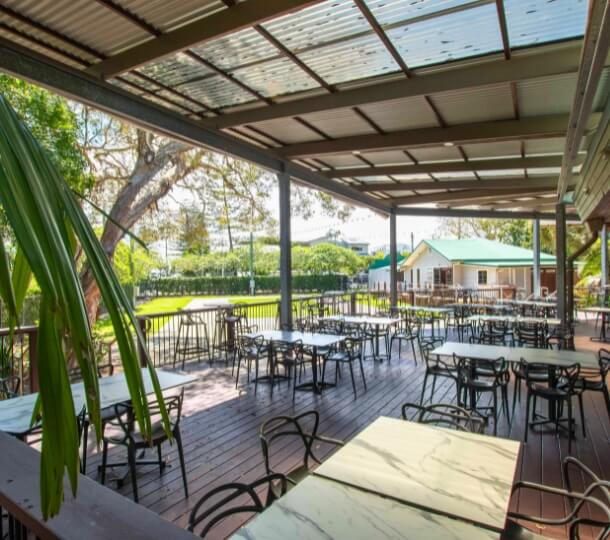 Outdoor patio with tables and chairs under a covered roof.
