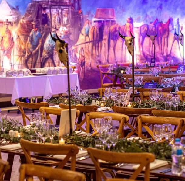 Long banquet tables with eucalyptus garlands, candles, glassware and cow skull centerpieces 