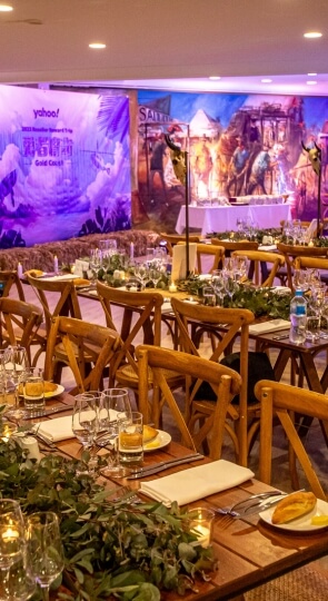 Sawrey Room banquet with wooden tables set for dinner, greenery and candle centerpieces, glassware and bread
