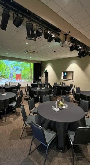 Sir Walter Campbell Theatre set for a reception: round tables with black cloths and centerpieces