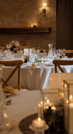 Elegant round wedding tables set with candles and beautiful glassware and tableware on white tablecloths