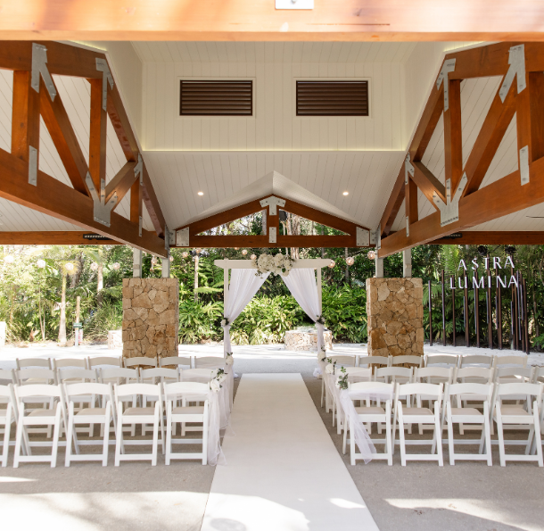 Elegant wedding reception set up in a rustic undercover outdoor venue, with green trees in the background
