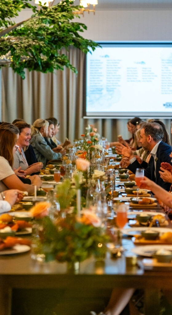 Guests enjoying a meal at a social event, gathered around a long dining table beautifully decorated in whimsical modern fitout