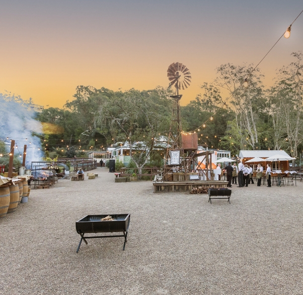 Outback Springs event venue at dusk with windmill, string lights and open fire pits at Currumbin Wildlife Sanctuary