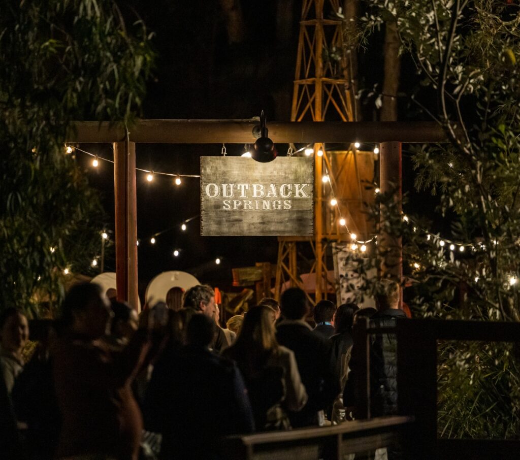 Guests entering Outback Springs under the illuminated venue sign at night, Currumbin Wildlife Sanctuary