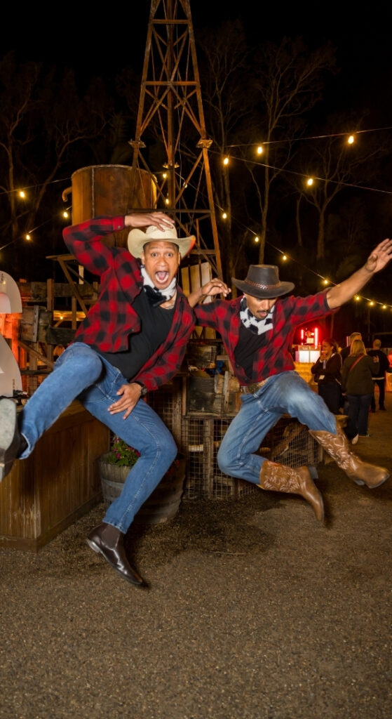 Two men dressed in cowboy hats and boots celebrating at an Outback Springs event