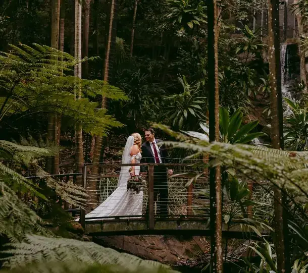 Bride and groom on a bridge surrounded by lush forest